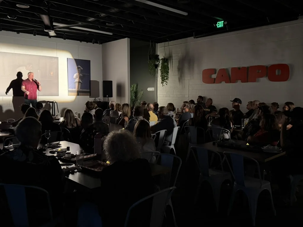 Derek Richards performing for a packed audience beneath the CAMPO sign at HOMES Campus